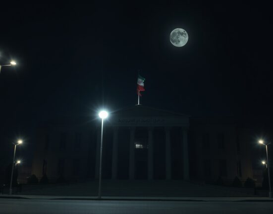 Iranian government building illuminated at night, reflecting geopolitical tension after US airstrikes