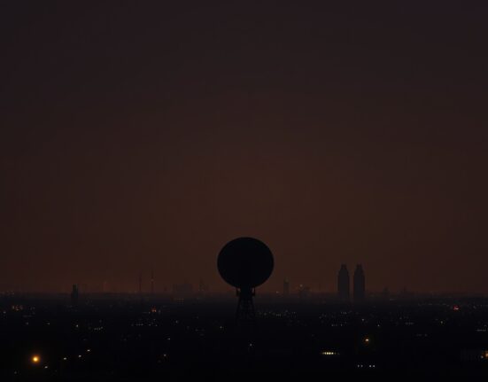 A military radar dish silhouetted against a hazy Middle Eastern skyline at dusk, representing heightened regional security tensions.