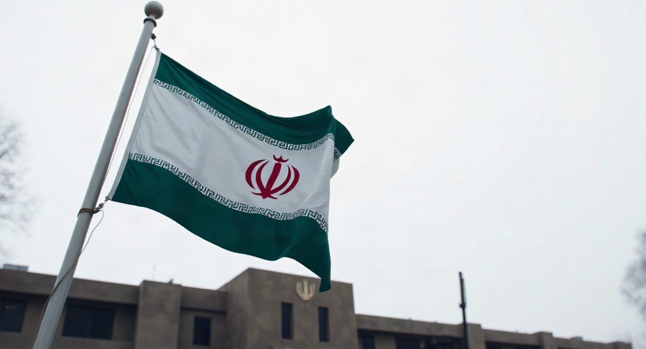 Iranian flag flying at a military base, symbolizing the IRGC's warning of a decisive response to aggression.