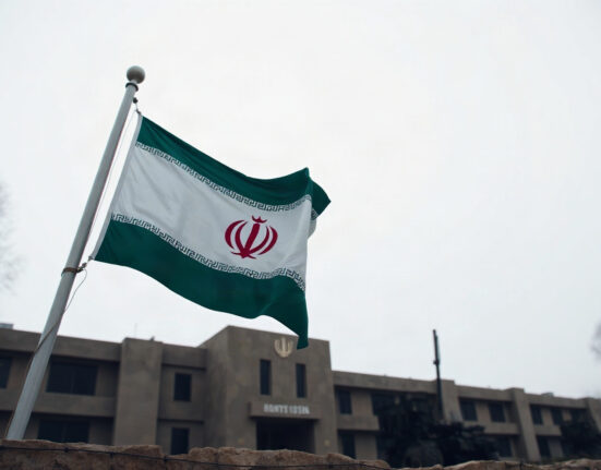 Iranian flag flying at a military base, symbolizing the IRGC's warning of a decisive response to aggression.