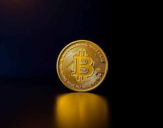 Bitcoin coin on a dark reflective surface with dramatic lighting