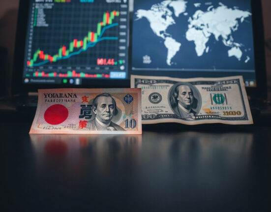 Japanese yen and US dollar banknotes with financial charts in background, representing currency intervention.