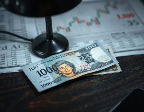 Japanese yen notes and US dollars on a desk with forex chart in background