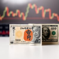 Japanese yen and US dollar banknotes side by side on a surface with financial chart background