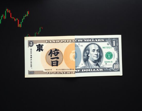 Japanese yen and US dollar banknotes on a dark surface with chart background