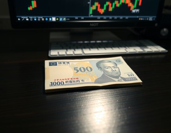 Japanese yen banknote on desk with forex chart and NFP indicator in background