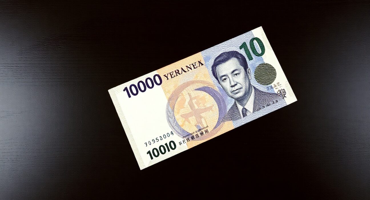 Japanese yen banknote and US dollar bill on dark wood surface