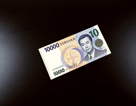 Japanese yen banknote and US dollar bill on dark wood surface