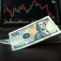 Japanese Yen and US Dollar banknotes on desk with a financial chart on monitor in background