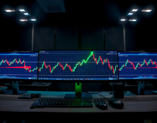 Crypto trading desk with monitors showing green upward charts, representing Jeffrey Huang's recovery.