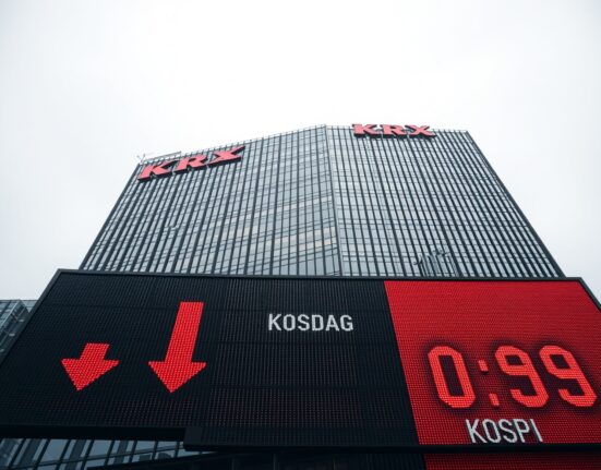 Korea Exchange headquarters in Busan with red stock ticker showing Kosdaq and KOSPI declines