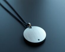 AI pendant device on dark surface with metallic finish and sensor