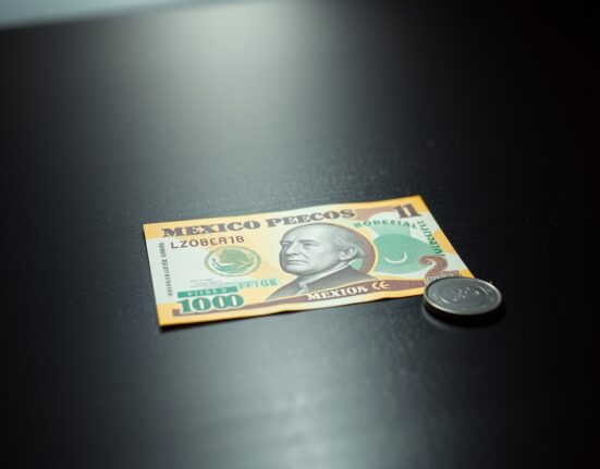Mexican peso banknote on a dark surface, representing currency pressure from Banxico's rate decision.