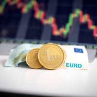 Norwegian krone coins and euro banknotes on a desk, representing the EUR/NOK exchange rate forecast.