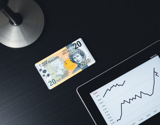 New Zealand Dollar banknote with a chart showing a downward trend, representing currency vulnerability.