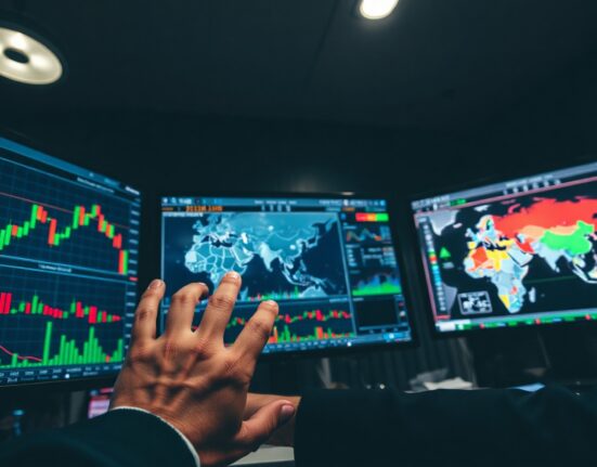 Trader monitoring oil and gold price charts amid geopolitical tensions