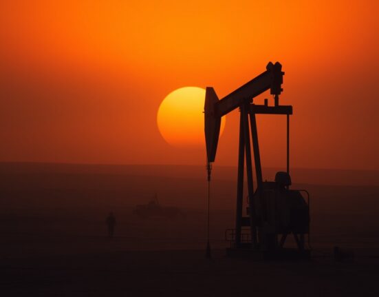 Oil pumpjack silhouetted against a hazy sunset sky, representing energy supply and geopolitical risk.