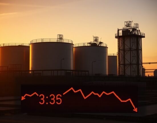 Oil storage tanks at sunset with digital price ticker showing declining crude oil prices