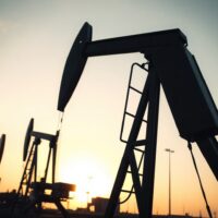 Oil pumpjack silhouetted against sunset, representing tightening supply and elevated crude prices.