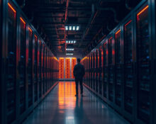 Data center corridor with server racks and a distant human silhouette