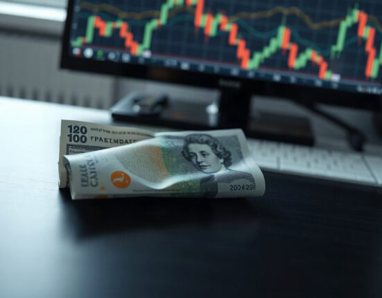 British pound and U.S. dollar banknotes on a desk with financial charts in the background