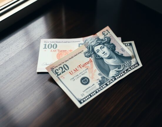 British Pound and US Dollar banknotes lying on a desk, representing the GBP/USD currency pair.