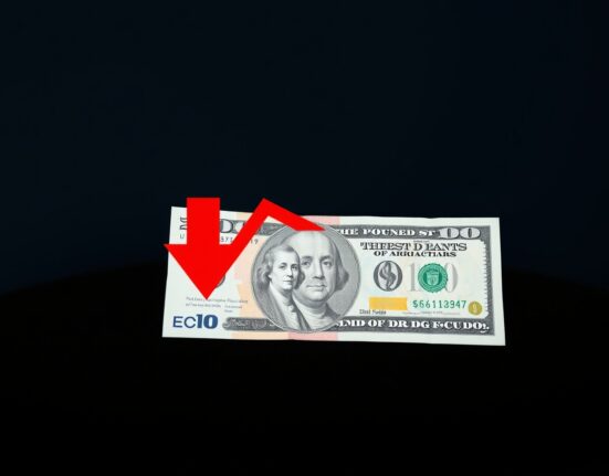 British Pound and US Dollar banknotes on a dark surface with a downward red arrow, representing the GBP/USD decline.
