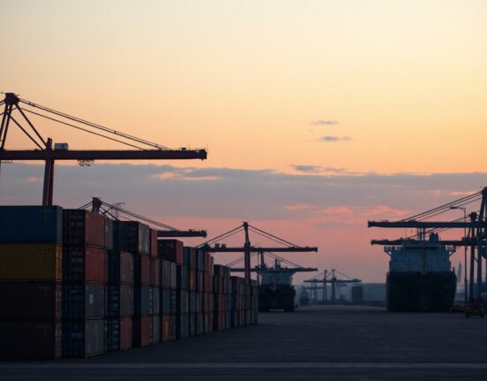 Cargo ship and cranes at a Russian port at dusk, symbolizing foreign trade activity.