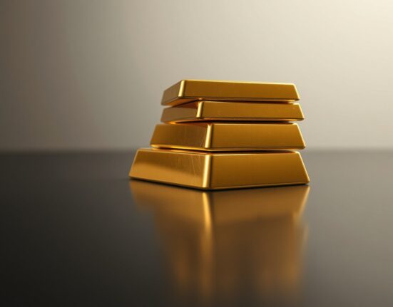 Close-up of gold bars reflecting light on a dark surface for a financial news article.