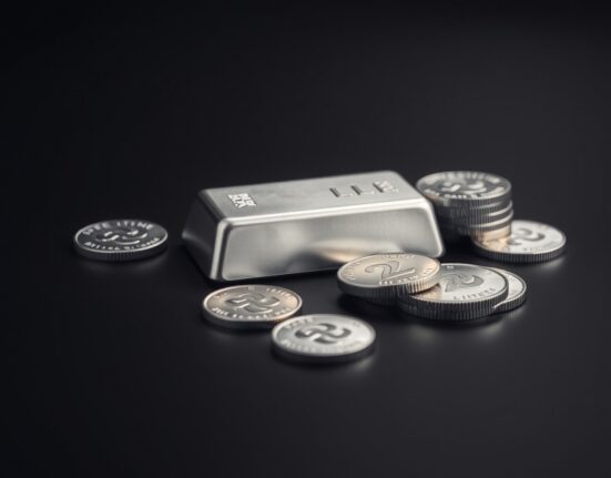 Silver bars and coins on a dark reflective surface, representing precious metals market and commodity investment.