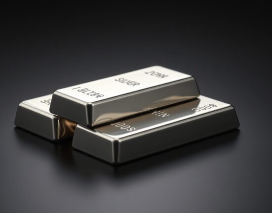 Stacked silver bullion bars on dark surface with soft lighting