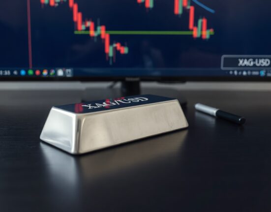 Silver bar with downward-trending XAG/USD chart in background representing falling precious metals prices.