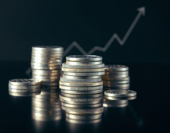 Close-up of silver bullion coins and bars on a reflective surface, representing the recent surge in silver prices.