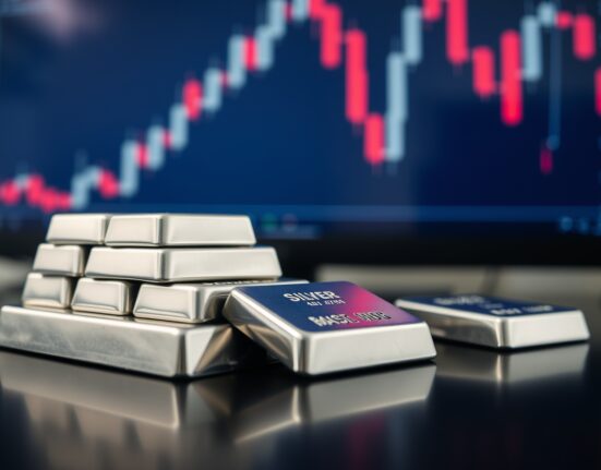 Stack of silver bullion bars with a financial chart showing a downward trend in the background