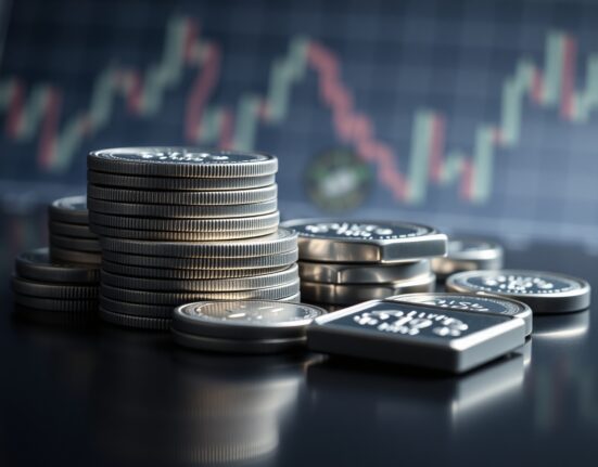Silver bullion coins and bars on a reflective surface with a financial chart in the background