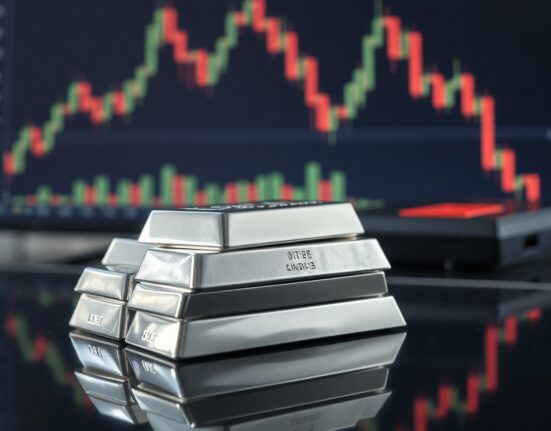 Stack of polished silver bars with a financial chart background, representing silver price movement.