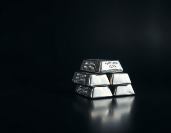 Stack of silver bullion bars on a dark surface with spotlight illumination