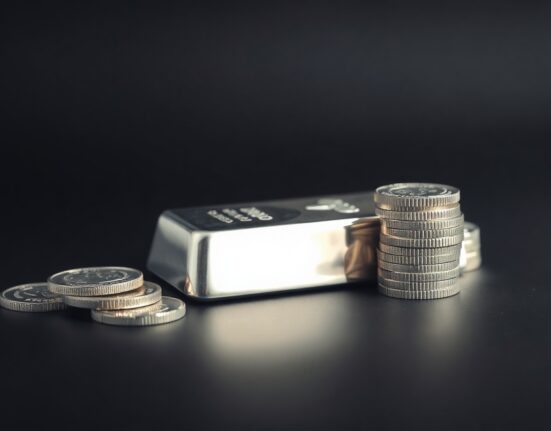 Close-up of a silver bar and coins on a dark surface representing the silver price rise today.
