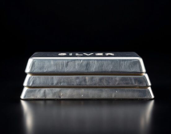 Stack of polished silver bars on a dark reflective surface, representing the silver market and precious metals trading.