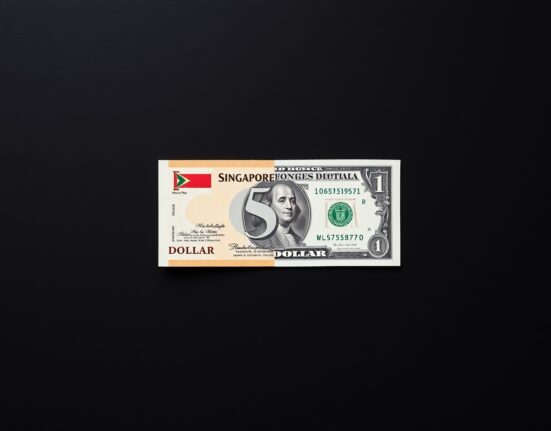 Singapore dollar and US dollar banknotes on a wooden surface representing currency exchange rate analysis.