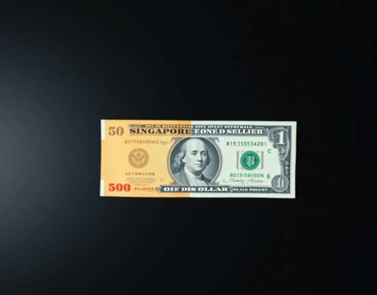Singapore dollar and US dollar banknotes side by side on a wooden surface