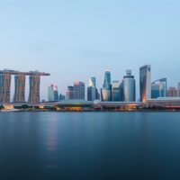 Singapore skyline at dusk with Marina Bay Sands and financial district, illustrating economic and policy analysis.