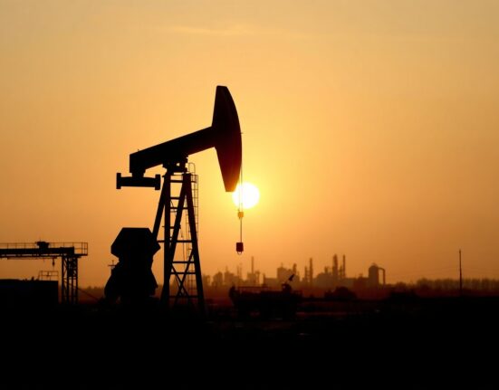 Oil pumpjack silhouetted against a sunset sky, representing gradual oil market recovery and geopolitical risk premium.