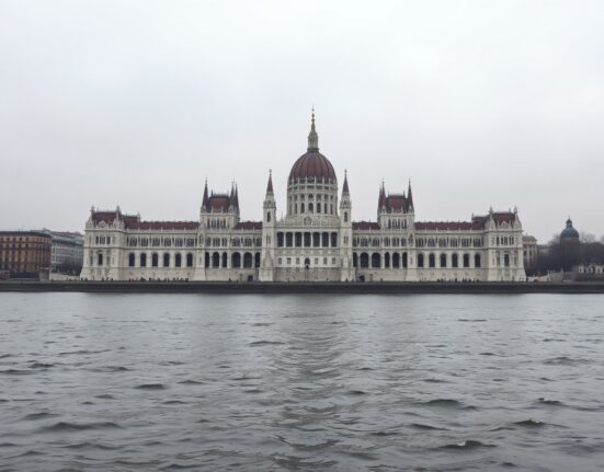 Hungarian Parliament building in Budapest, Hungary, on a cloudy day, representing economic policy and the Forint.