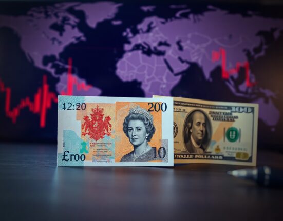 British Pound and US Dollar banknotes on a desk with a blurred financial background