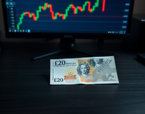British Pound Sterling banknote on a desk with a financial chart in the background