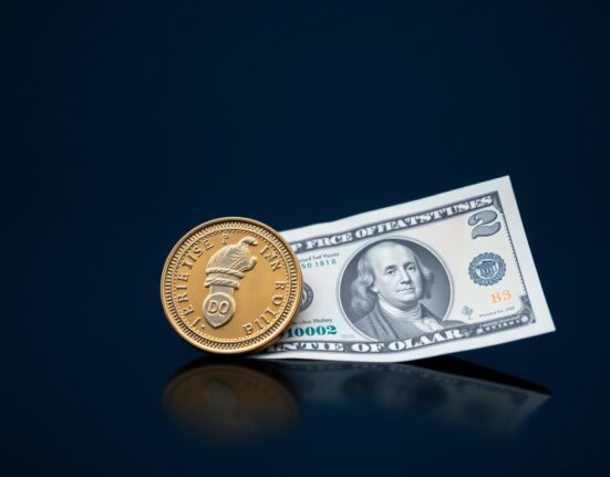 British pound coin and US dollar bill on reflective surface