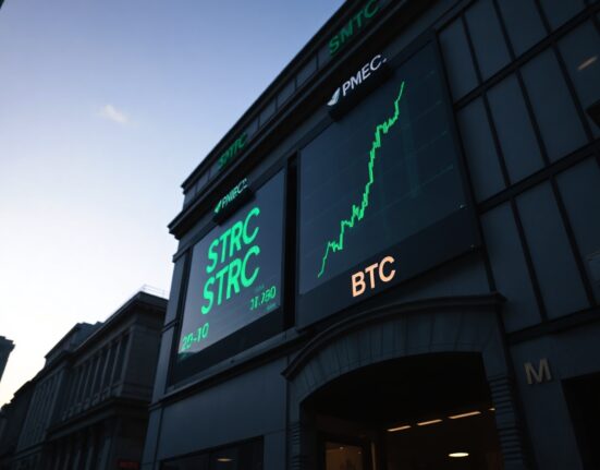 Stock market ticker showing STRC and BTC prices with upward green numbers in a financial district