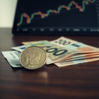 Swedish Krona coins and banknotes on a desk with a financial chart in the background