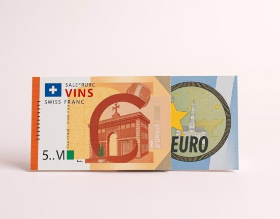 Swiss franc and euro banknotes side by side with financial charts in background